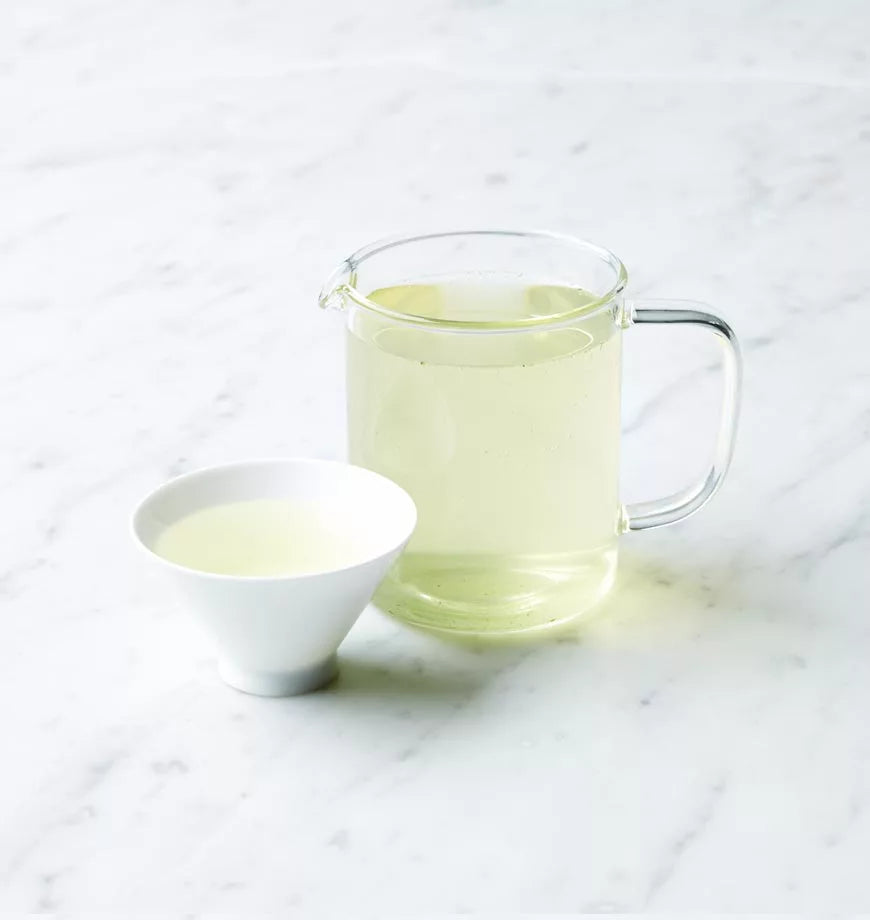 A pitcher of organic Gyokuro Japanese green tea beside a delicate cup filled with the same tea.