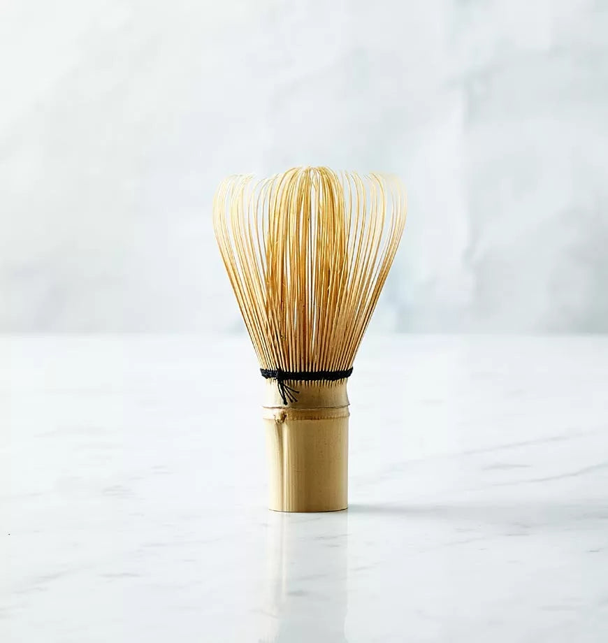 Bamboo Bai Chasen matcha tea whisk with a straw resting on top, showcasing its wooden texture and design.