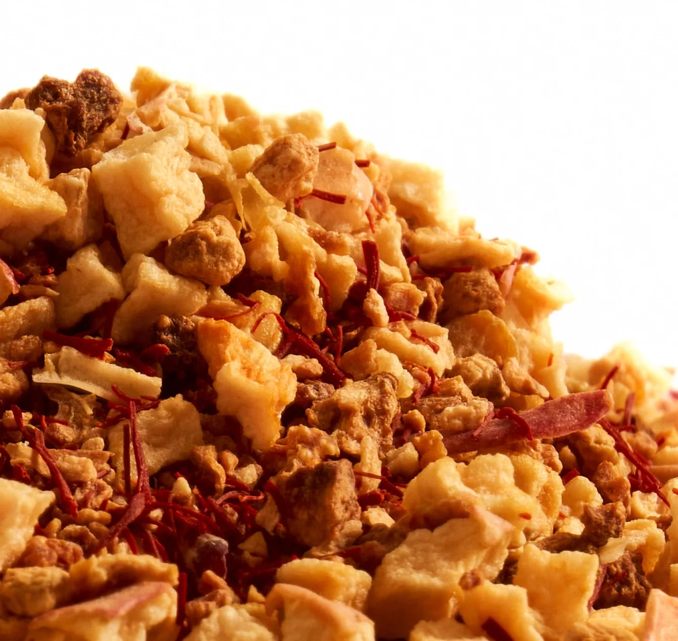 A pile of nuts and dried fruit on a white background, representing the Saffron Rapture herbal infusion blend.
