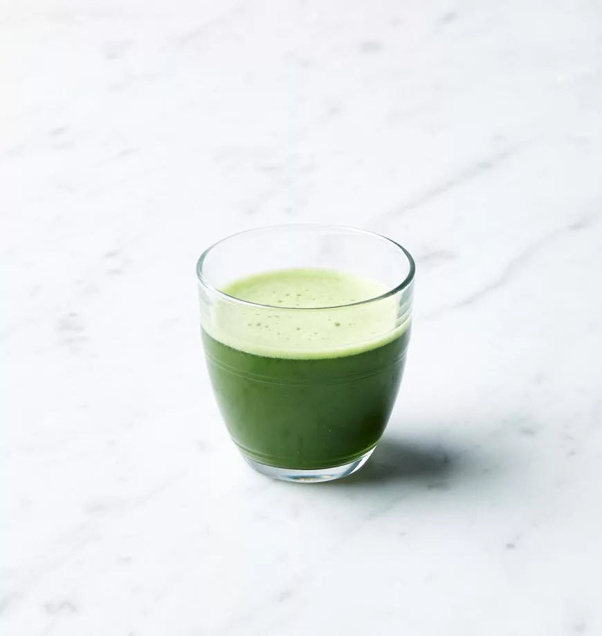 Glass of organic green tea made with Super Uji Matcha sits on a polished marble counter.