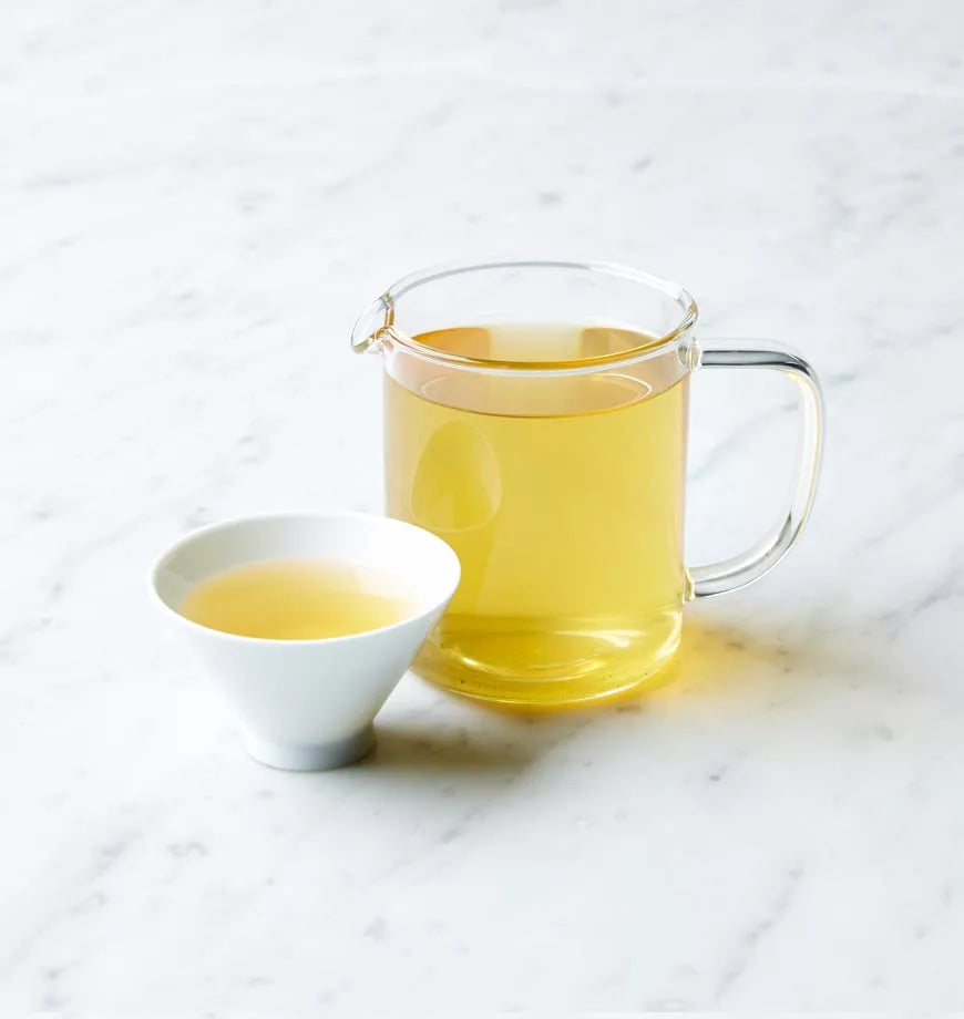 A cup of organic Jasmine Green Tea beside a pitcher filled with the same fragrant green tea.