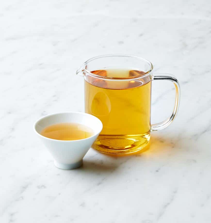A cup of oolong tea and a pitcher of tea on a marble counter, showcasing a serene tea setting at Four Seasons.