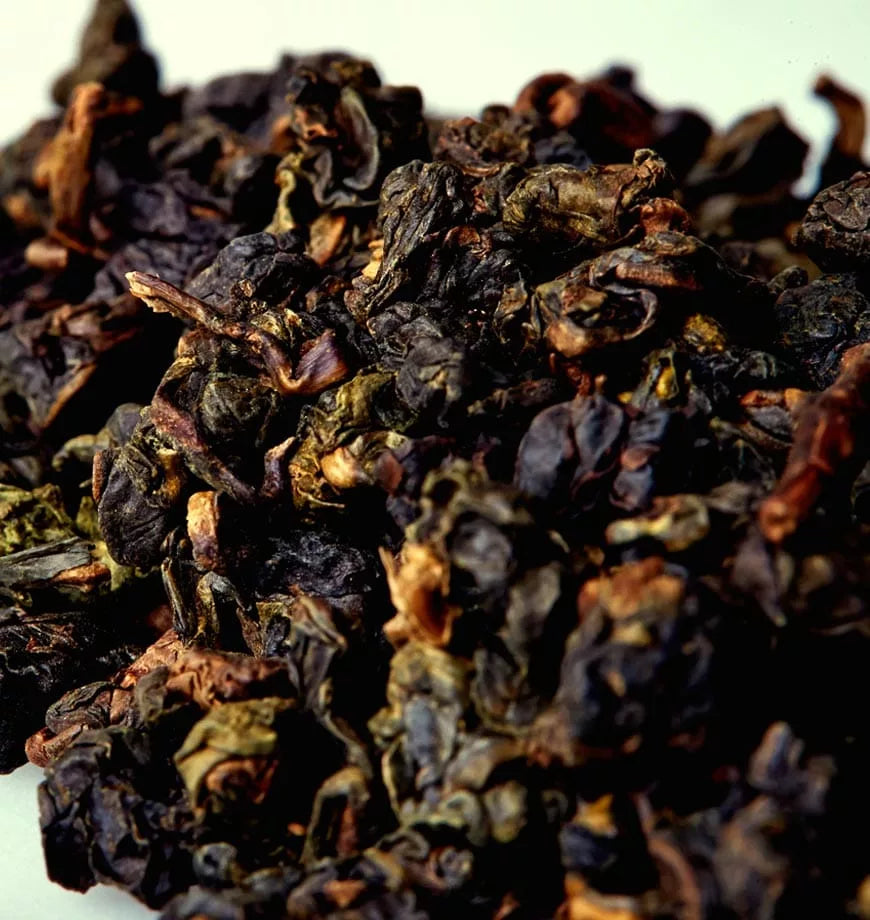 A collection of dried black tea leaves, identified as Iron Goddess of Mercy oolong, emphasizing their deep color and texture.