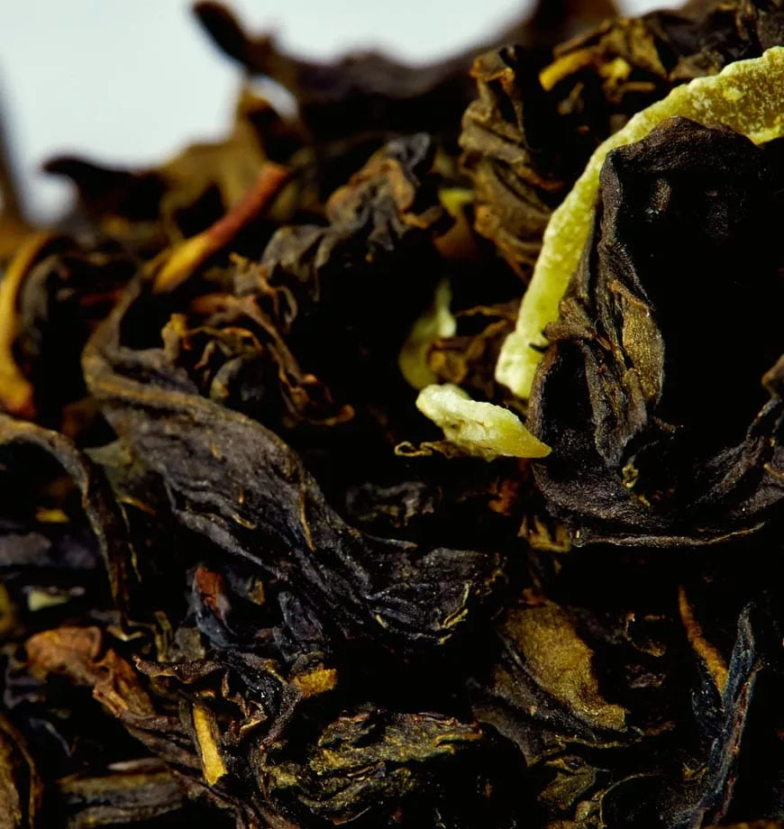 A detailed view of black tea leaves interspersed with yellow leaves, representing Pineapple Coconut oolong tea.