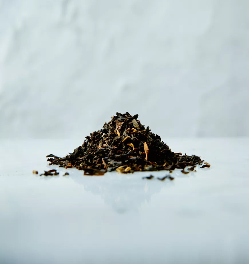 A pile of loose English Breakfast black tea leaves on a white surface.