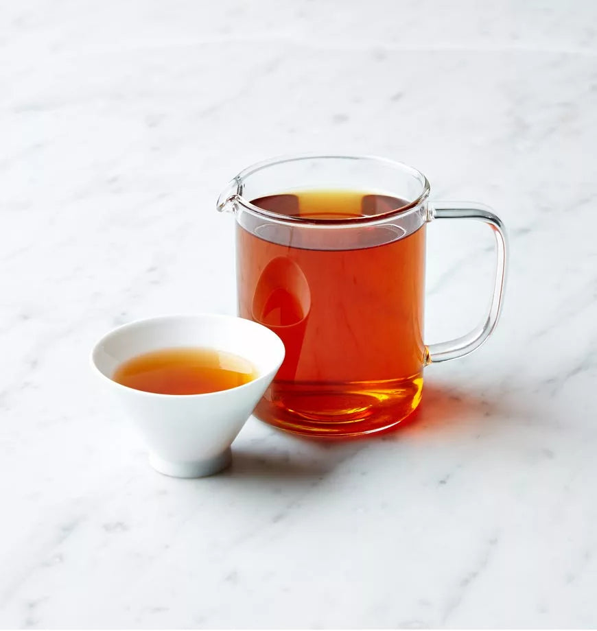 A cup of Earl Grey tea and a pitcher of tea placed on a polished marble counter.