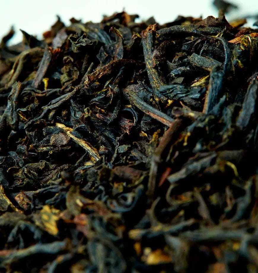 A pile of Bodacious Black Tea leaves on a clean white surface, showcasing their rich color and texture.