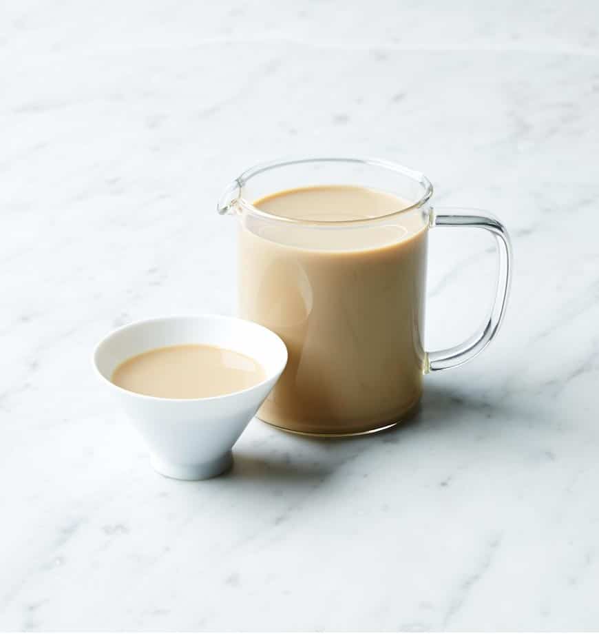 A pitcher of tea alongside a cup of tea, featuring a subtle presence of organic chai tea in the scene.