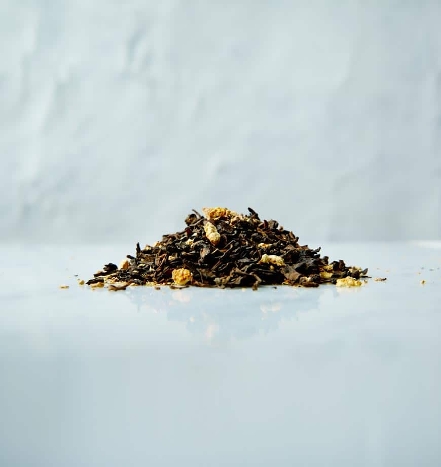 A pile of black tea mixed with dried orange peels, labeled as Blood Orange Pu-erh Tea