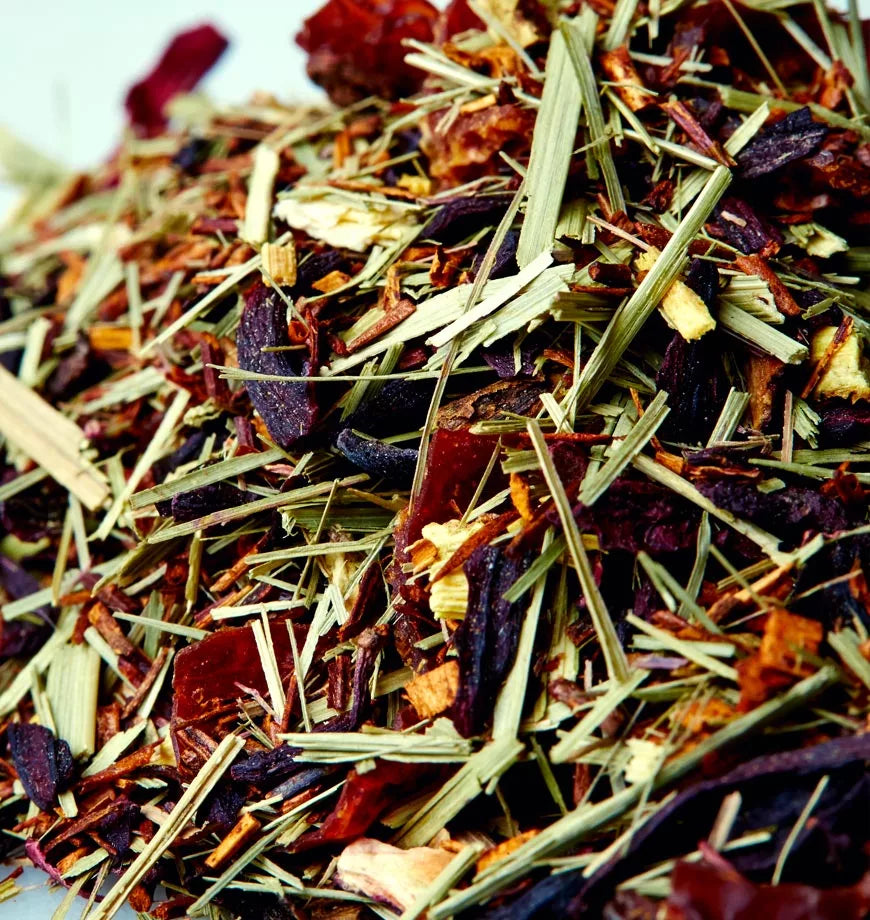 A white surface featuring a pile of dried herbs and leaves, identified as Hibiscus Bliss herbal infusion.