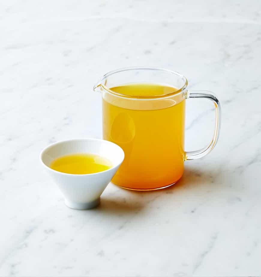 A pitcher and a bowl of orange juice, with a label indicating Turmeric Spice herbal infusion nearby.