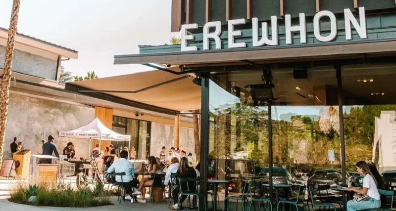 People seated outside Erewhon restaurant, showcasing the exterior and a sign that Samovar tea is now available.