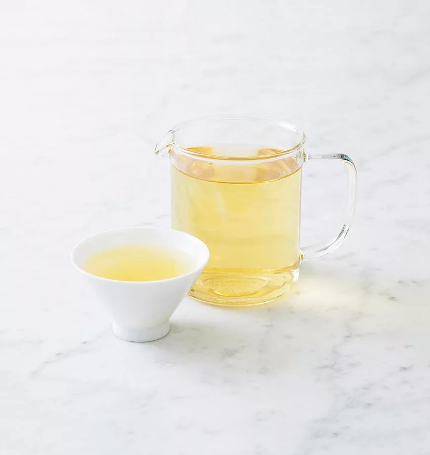 A pitcher of organic Bancha green tea next to a cup, highlighting a serene tea-drinking experience.