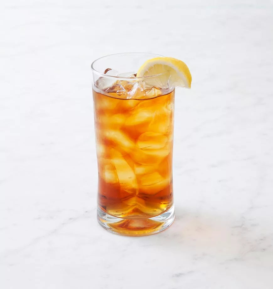 A glass of iced black tea with lemon slices sits on a marble surface, showcasing organic black tea.