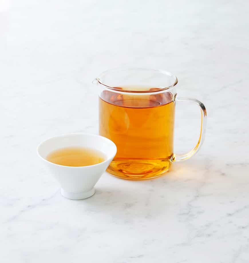 A cup of Peppermint Superior herbal tea and a pitcher on a marble surface, showcasing a calming tea setting.