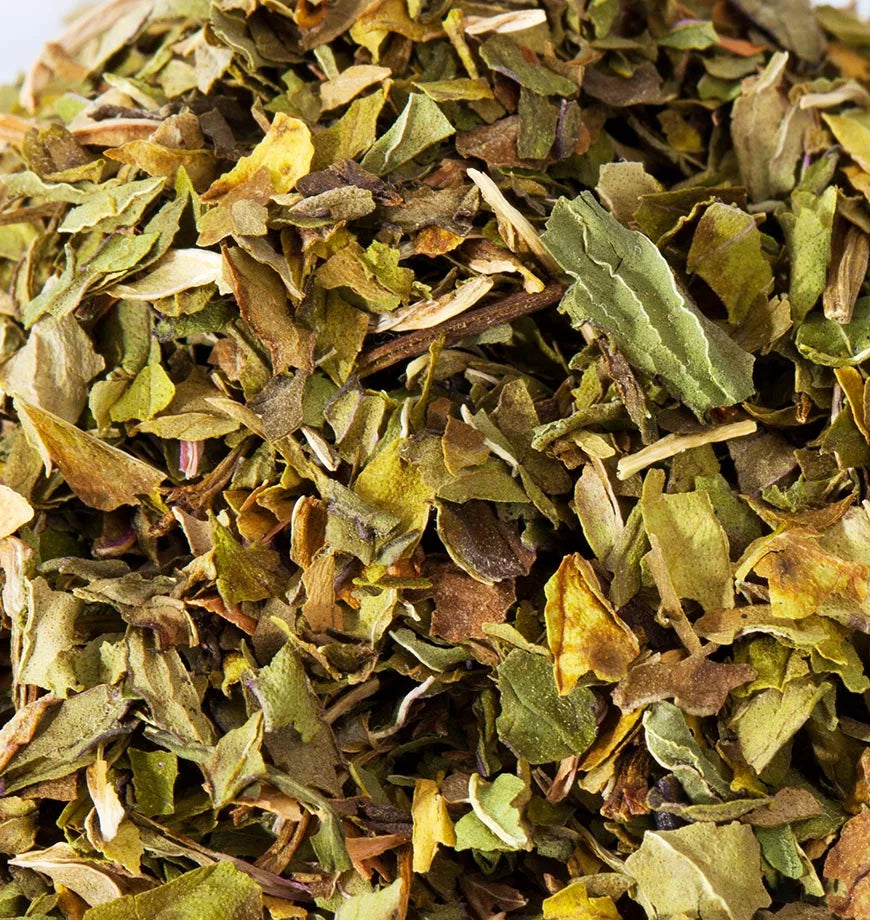 A collection of dried peppermint leaves on a white surface, illustrating their texture and color for herbal infusion preparation.