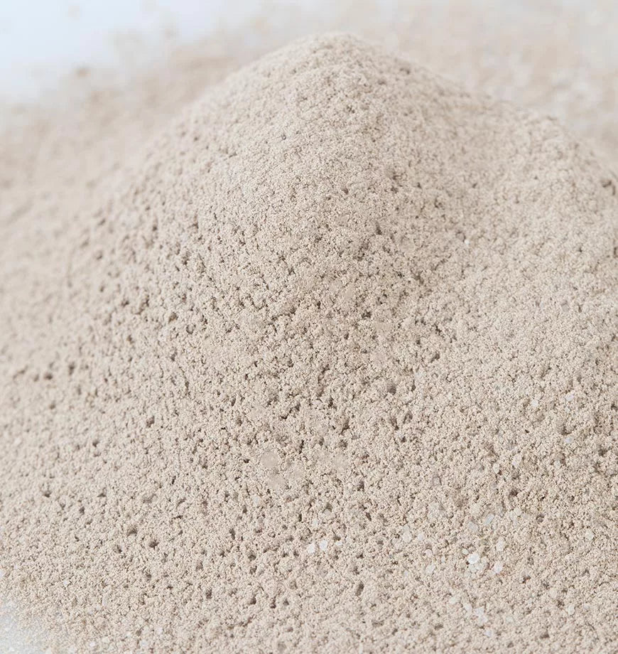 A small pile of houjicha powder resembling sand, placed on a clean white surface.